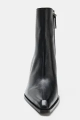 Botín estilo cowboy de piel color negro, con caña baja, acabado en punta y tacón medio en bloque. Cuenta con cierre mediante cremallera lateral.