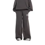 Pantalón de jogging New Balance de corte ancho y tiro alto, color gris oscuro, con cintura elástica y logo de la marca estampado en blanco en la pierna izquierda.