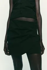 Falda pantalón negra de tiro alto con diseño cruzado y pliegues drapeados en el frente.