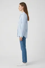 Camisa de manga larga color blanco, con cuello camisero, cierre frontal de botones y diseño clásico.