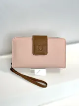Billetera grande de cuero rosa con cierre de cremallera y correa de muñeca marrón. Tiene un aplique marrón con el logo de la marca en el frente.