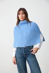 Capita tejida en punto acanalado color celeste, con cuello alto y aberturas laterales.
