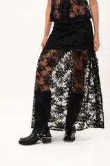 Pollera larga de encaje negro con silueta fluida y diseño asimétrico. Presenta un forro interno hasta la altura del frunce, dejando la parte inferior con transparencias que aportan movimiento.