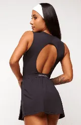 Vestido deportivo negro sin mangas, con escote en V y logo estampado en el pecho. Falda corta con short interno y bolsillos laterales. Incluye protección UV50+.