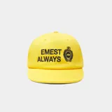 Gorra amarilla con visera curva, confeccionada en algodón. Cuenta con bordado frontal con el texto "EMEST ALWAYS" y un escudo distintivo en negro.