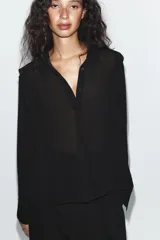 Camisa negra fluida de manga larga, cuello solapa y cierre frontal oculto con botones.