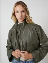 Chaqueta de eco cuero color verde militar, marca Elan. Presenta cuello alto con broches, cierre frontal con cremallera y botones a presión, y bolsillos de solapa en el pecho. Tiene forro interno a tono.