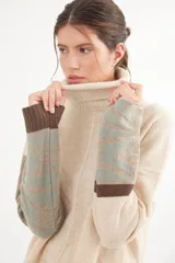 Polera de calce relajado con cuello alto, confeccionada en lana. Presenta un diseño bicolor con cuerpo en gris claro y mangas con estampado jacquard de arabescos en tonos tierra y negro. Incluye detalle de costura central vertical en el frente.