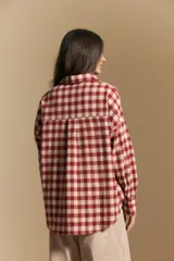 Camisa de estilo leñador con estampado de cuadros en tonos azul, negro y marrón. Presenta cuello clásico, cierre frontal con botones y mangas largas con puños abotonados.