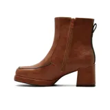 Bota de vestir de caña media en color marrón, con taco cuadrado y plataforma delantera. Presenta un diseño minimalista con costuras visibles y detalle de borde en color negro.