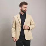 Saco de gabardina color beige, con solapa de muesca, cierre de dos botones, dos bolsillos de parche frontales y un bolsillo en el pecho.