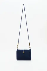 Cartera tipo sobre de algodón azul marino con bordados de motivos celestiales como lunas y estrellas en tonos dorados y plateados. Incluye una correa larga trenzada, cierre superior con cremallera y un detalle de borla decorativa en el lateral.