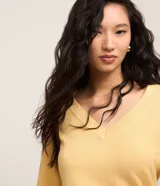 Suéter de punto color amarillo, con escote en V y mangas largas. Presenta un diseño básico y versátil, confeccionado en una mezcla de viscosa, poliamida y elastano.