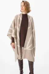 Ruana de tejido de punto con diseño geométrico de líneas curvas en tonos beige y visón. Presenta una caída fluida y envolvente, ideal para usar como capa sobre otras prendas.