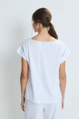 Pijama de dos piezas en color blanco, confeccionado en algodón. Incluye una remera de manga corta con cuello en V y detalles de calados, y un pantalón de corte recto con detalles de calados en el ruedo.