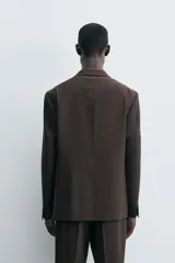 Blazer de corte regular fit confeccionado en tejido con lana. Presenta cuello con solapas de muesca, cierre frontal de un botón, bolsillos de vivo en el pecho y en la cadera, y aberturas en la espalda.