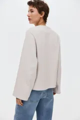 Buzo oversized color beige claro de punto interlock pesado, con cuello redondo y mangas largas amplias.