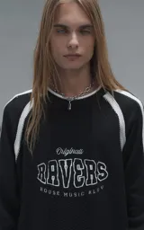 Sweater de punto negro con cuello redondo, mangas largas con franjas laterales blancas y puños en punto rib. Presenta un diseño gráfico bordado en el pecho con la inscripción 'RAVERS' y detalles en blanco.