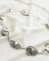 Cinturón plateado ajustable con eslabones ovalados decorados con cráneos de toro.