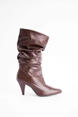 Bota de caña media con diseño slouchy, confeccionada en cuero marrón, con punta fina y taco cónico.