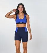 Conjunto deportivo compuesto por un top de escote redondo con espalda estilo nadador y un short de tiro alto. Ambas piezas presentan un diseño bicolor en azul eléctrico y azul marino, confeccionadas en tejido acanalado con el logo de la marca estampado en el frente del top.