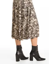 Vestido midi de seda fría con estampado animal print. Presenta cuello con solapa, escote en V con cierre frontal de botones, mangas cortas con terminación fruncida y lazo de ajuste en la cintura.