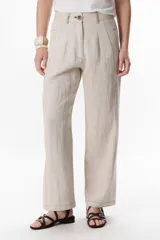 Pantalón de lino color beige claro, tiro alto, corte recto y holgado, con pinzas delanteras y pespuntes visibles a contratono.
