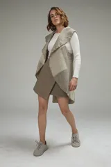 Chaleco sin mangas de tejido de lana fina sin teñir, con diseño circular y bloques de color beige y marrón. Presenta un cuello amplio y solapa que permite usarlo como chaleco largo o capa corta.