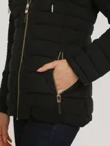 Campera acolchada de corte entallado, con capucha ajustable mediante cordones, cierre frontal de cremallera y bolsillos laterales con cierre. Presenta un diseño de líneas horizontales y detalles metálicos distintivos de la marca.