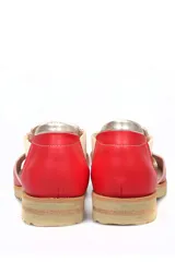 Zapato tipo sandalia plana de cuero liso en color rojo cereza con detalles en color crema. Presenta paneles laterales elásticos, suela dentada y diseño con aberturas.
