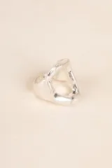 Anillo plateado con forma geométrica irregular y diseño moderno.