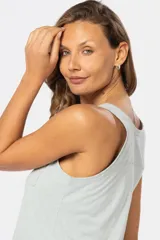 Musculosa blanca sin mangas, de corte clásico y calce cómodo, confeccionada en tejido suave. Presenta escote redondo, cartera con botones frontales y un pequeño bolsillo aplicado en el pecho.