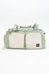 Bolso deportivo verde con detalles en gris y beige. Tiene doble asa de mano y correa de hombro ajustable. Cuenta con dos bolsillos frontales con cierre y logo de la marca en la esquina inferior derecha.
