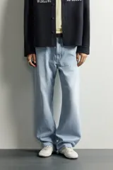 Jeans de denim de algodón en color azul con efecto desgastado, tiro medio y corte recto de ajuste holgado (loose fit). Cuenta con diseño clásico de cinco bolsillos y cierre frontal con cremallera y botón.
