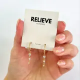 Aros dorados de plata 925 con forma de argolla con pequeños brillantes y tres dijes colgantes con forma de corazón y brillantes.