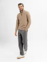 Buzo de tejido de punto color beige con cuello alto y cierre frontal parcial. Presenta puños y ruedo acanalados.