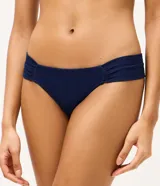 Bombacha de bikini azul marino confeccionada en microfibra texturizada, con laterales drapeados y anchos que aportan mayor comodidad. Cuenta con forro interno y detalle de medalla metálica en la parte posterior.