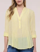 Blusa de gasa bambúla color amarillo, marca Zac & Rachel, con cuello a la base y escote en V con botones frontales. Presenta diseño delantero plisado y mangas largas con sistema de ajuste mediante presilla.