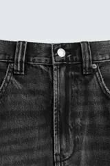 Bermuda de denim de algodón, color negro lavado, de corte ancho (baggy fit) y tiro medio. Presenta cinco bolsillos y bajo con acabado irregular deshilachado.