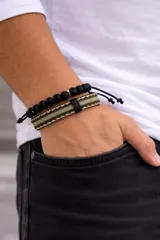 Set de dos pulseras para hombre, una compuesta por cuentas esféricas negras y la otra de cadena metálica trenzada en color gris oscuro.