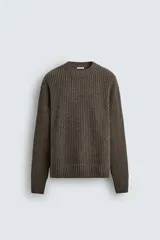 Jersey de corte relajado confeccionado en una mezcla de algodón y lana. Presenta cuello redondo, manga larga y acabados en rib en puños y ruedo, con una textura de punto acanalado.
