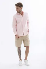 Camisa rosa de manga larga con cuello clásico y cierre frontal con botones. Corte recto.