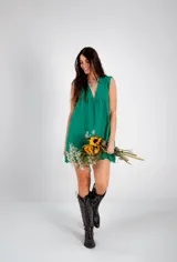 Vestido corto verde esmeralda con bordado calado, escote en V, sin mangas y corte evasé.