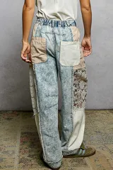 Pantalon tipo barrel en denim lavado claro con efecto acid wash, corte holgado y detalles combinados en los laterales con tela a rayas y encaje.