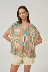 Blusa de lino con diseño estampado multicolor en tonos tostado, turquesa y rosado, corte holgado, mangas cortas y escote en V.