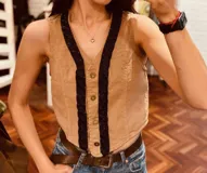 Chaleco color beige de pana con botones y ribete de cuentas negras.