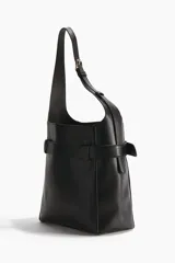 Cartera tote negra de tejido revestido, con cierre magnético y correa de hombro ajustable. Presenta una correa decorativa exterior con hebilla metálica dorada y ojetes alrededor, además de compartimento interior con cierre y forrería.