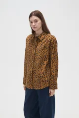 Camisa de algodón con estampado de manchas oscuras sobre fondo tostado, de corte holgado, manga larga, cuello clásico y cierre frontal con botones.