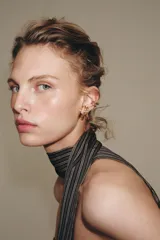 Set de cuatro pendientes metálicos dorados que incluye un par de aros triples con cierre de tuerca, un earcuff de aro doble y un earcuff de aro triple con detalle de cristal.