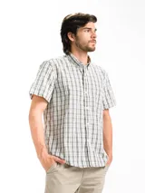 Camisa de hombre de manga corta con estampado a cuadros en tonos blanco, verde y marrón. Tiene cuello abotonado y bolsillo en el pecho.